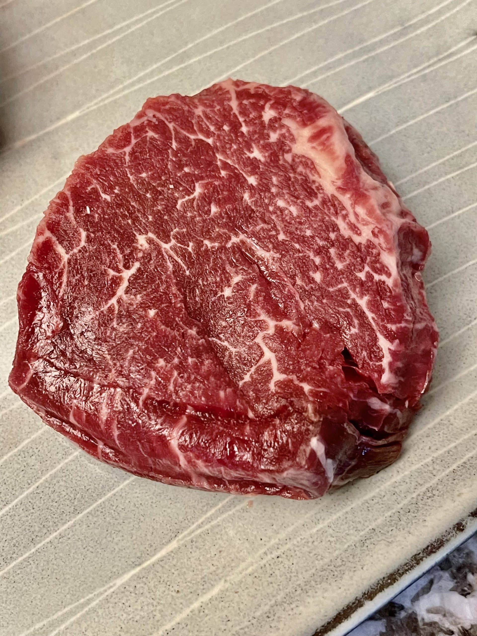A close up of a fresh cut, Wagyu steak on butcher paper.